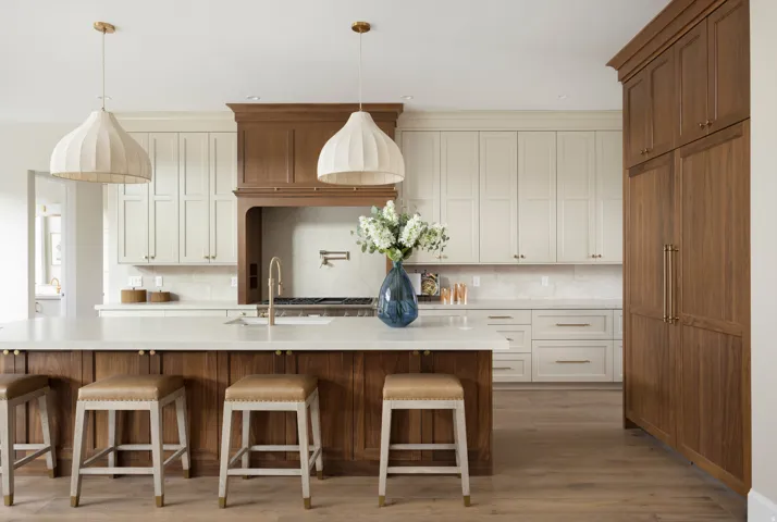 Gourmet kitchen featuring a wood-finish island with a light-toned countertop, dual-tone cabinetry, brass hardware, and wood-finish flooring