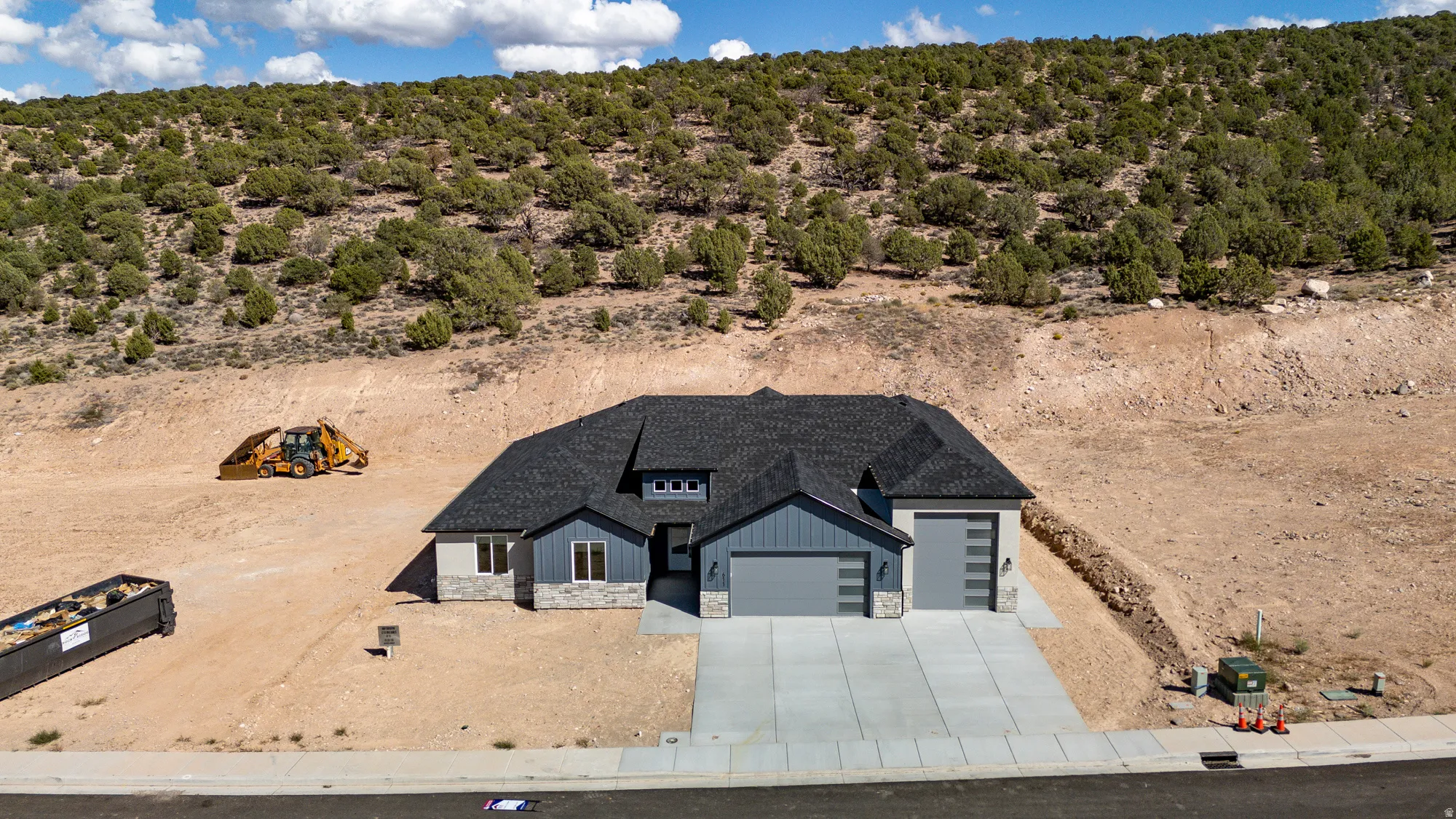 Contemporary home with a dark shingle roof, light grey siding, stone accents, and a two-car garage