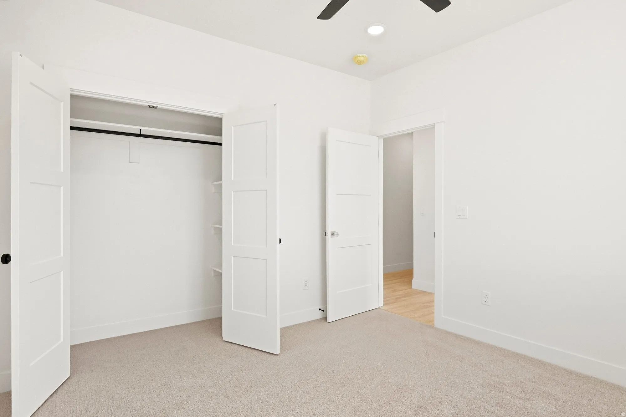 Wall-to-wall carpeting, three-panel interior doors, and a ceiling fan with integrated lighting