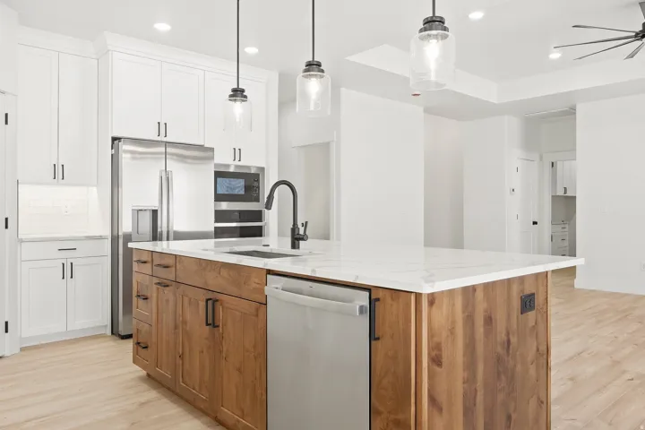 Kitchen featuring a central island with wood cabinetry, stainless steel appliances, white perimeter cabinetry, and an undermount sink