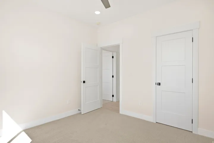 Recessed ceiling lighting, neutral carpet, white interior doors with flat panel design, contrasting door hardware, and trim molding