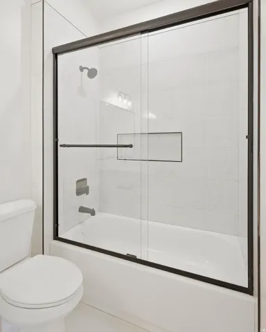 Tub and shower combination with sliding glass doors, a recessed shelf, and an overhead shower fixture