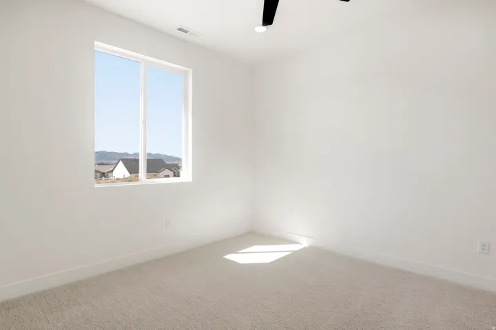 Natural light, light-toned carpeting, white walls, modern ceiling fan, and mountain backdrop