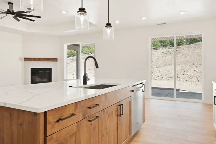 Kitchen island with stone countertop, integrated sink, and modern pendant lighting