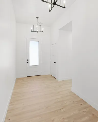 Entryway featuring wood-finish flooring, white walls, and a modern chandelier