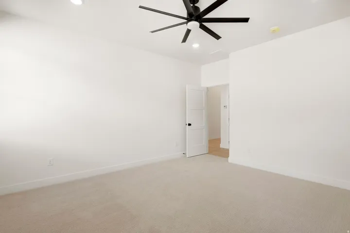 Recessed lighting, ceiling fan, white paneled door, light-toned carpeting, and wood-finish flooring visible beyond