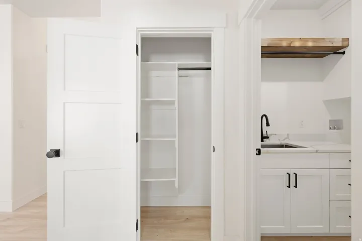 Laundry area featuring white cabinetry, a sink with a matte black faucet, and a light wood-finish shelf