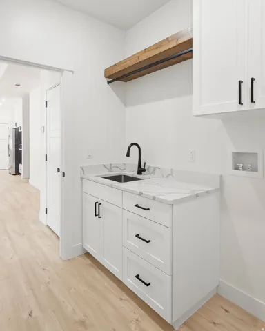 White cabinetry with matte black hardware, integrated sink, and stone-finish countertop