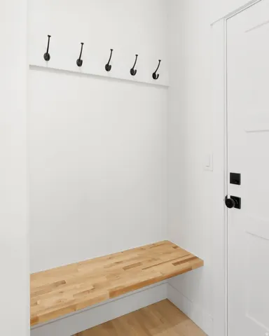 Built-in wood-finish bench with overhead coat hooks