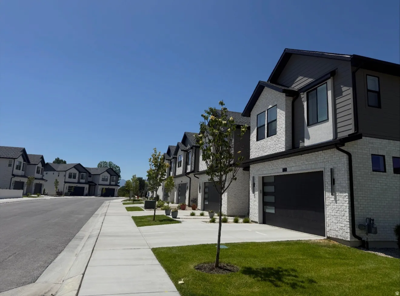 Modern residential exterior featuring a white brick facade and dark gray siding