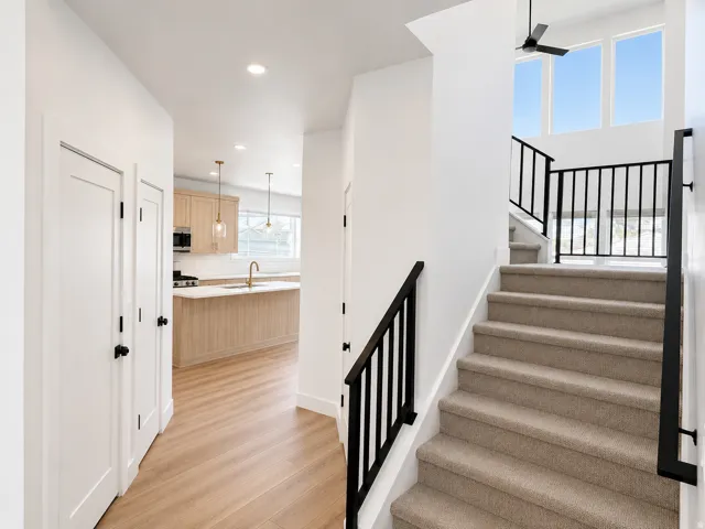 Staircase with black metal railings, carpeted treads, and prominent upper-level windows