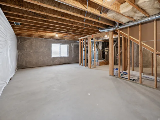 Unfinished basement offering substantial expansion potential with exposed ceiling joists, concrete flooring, perimeter insulation, and a lower-level window