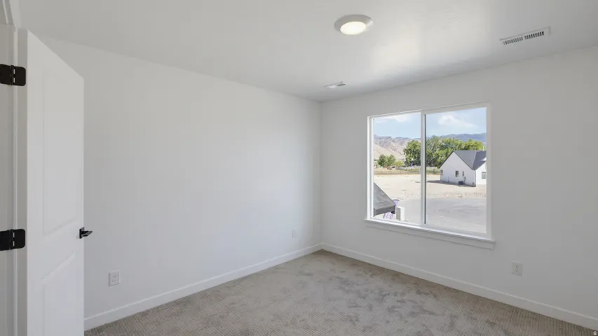 White interior walls, recessed ceiling lighting, light grey carpeting, and a white-framed window