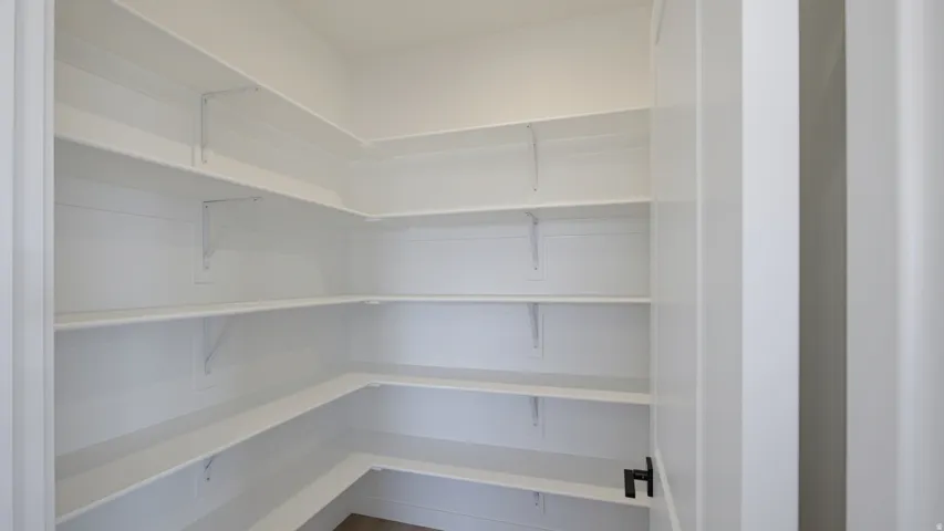 White built-in shelving, multi-tiered shelving, corner shelving, white walls, and a dark door handle