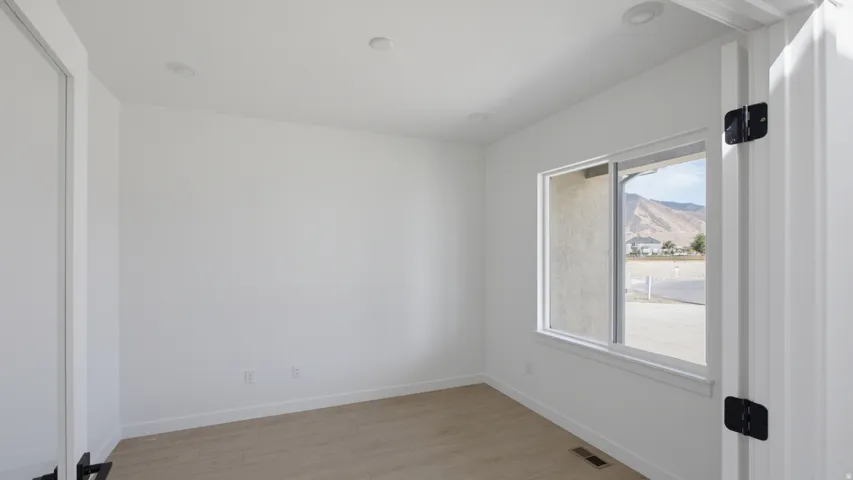 Recessed ceiling lighting, wood-finish flooring, and a large window with white trim