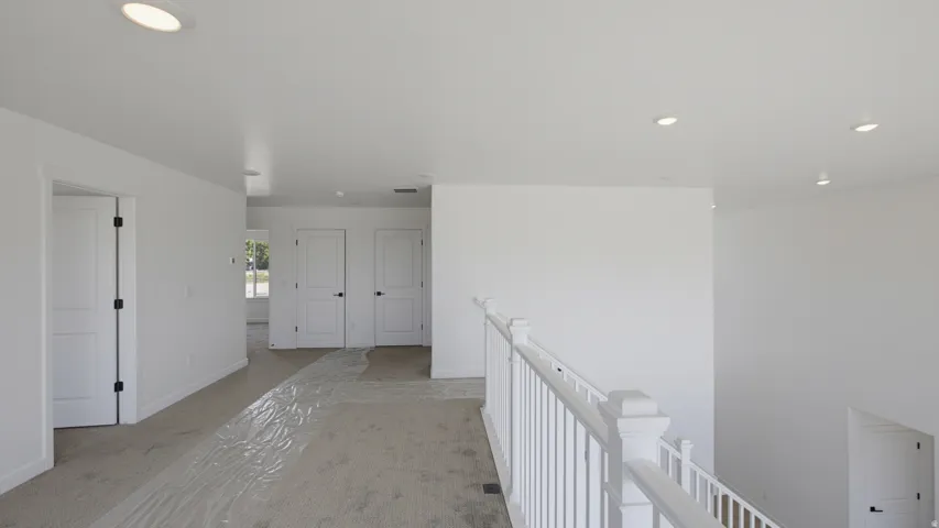 Recessed lighting, white walls, white doors, black door hardware, white banister