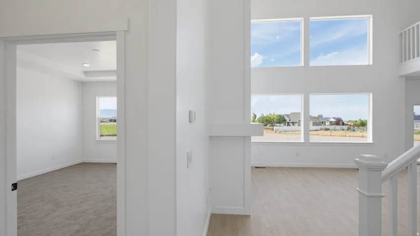 Two-story great room with abundant natural light, wood-finish flooring, and a contemporary white railing