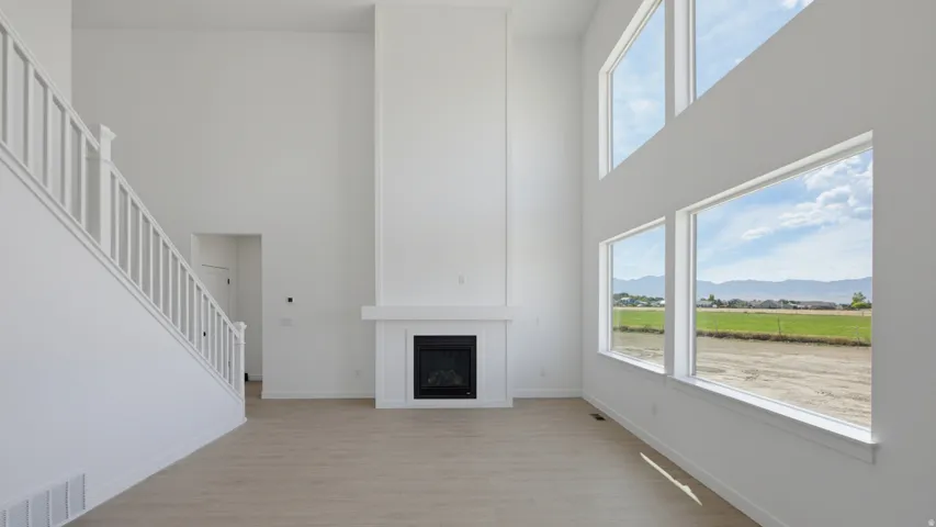 Two-story interior with high ceilings, a built-in fireplace, staircase with white banister, and large windows