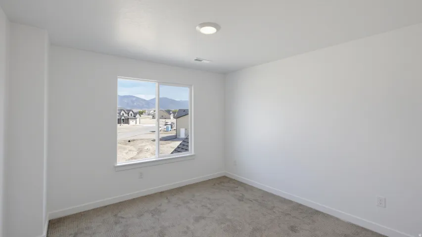 Recessed ceiling lighting, a large window, and light-colored carpeting