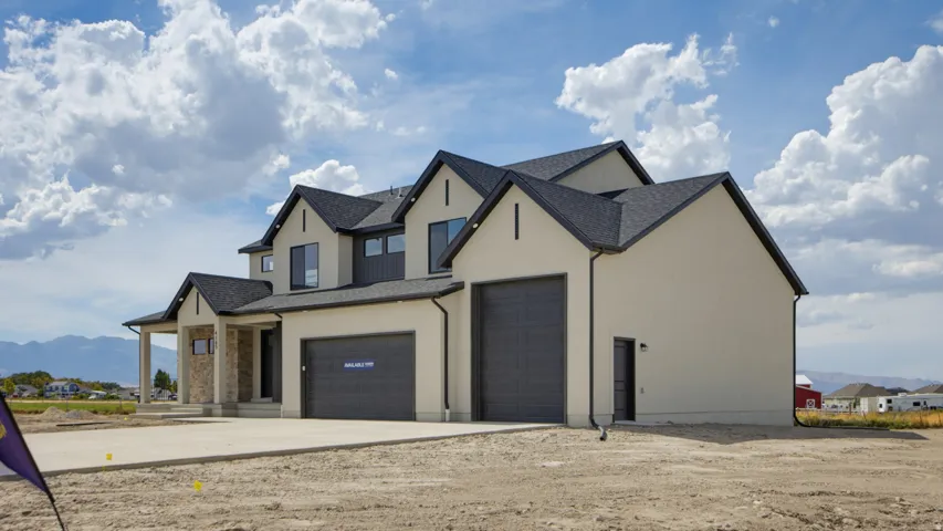 Two-story residence featuring a dark gray shingle roof, light-colored stucco exterior, and stone column accents