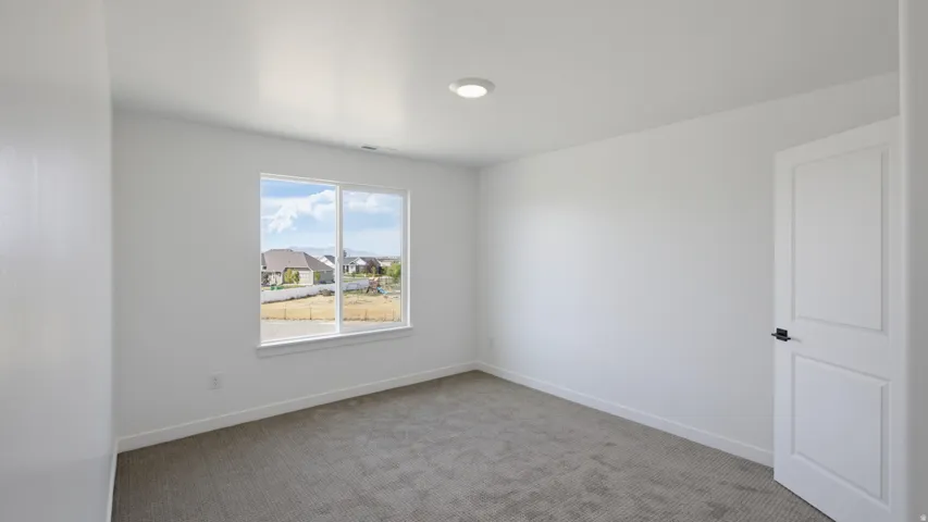 Neutral-toned carpet flooring, white walls, recessed ceiling light, white trim, and a window with a rural landscape