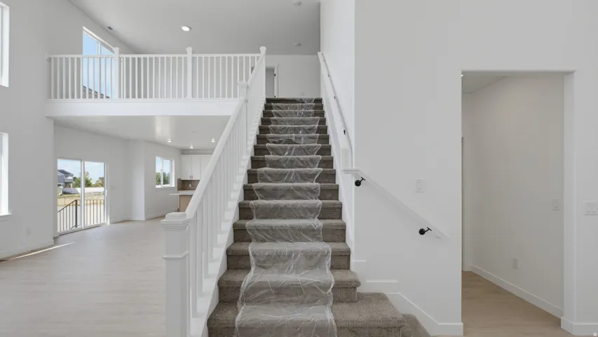 Open-concept interior featuring a two-story ceiling, light wood-finish flooring, and a second-story overlook with white balusters