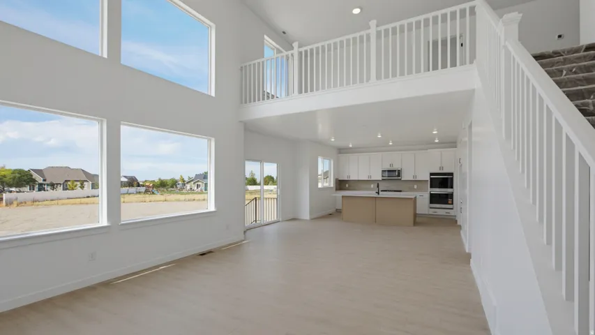Two-story living area with high ceilings, multiple large windows, and wood-finish flooring