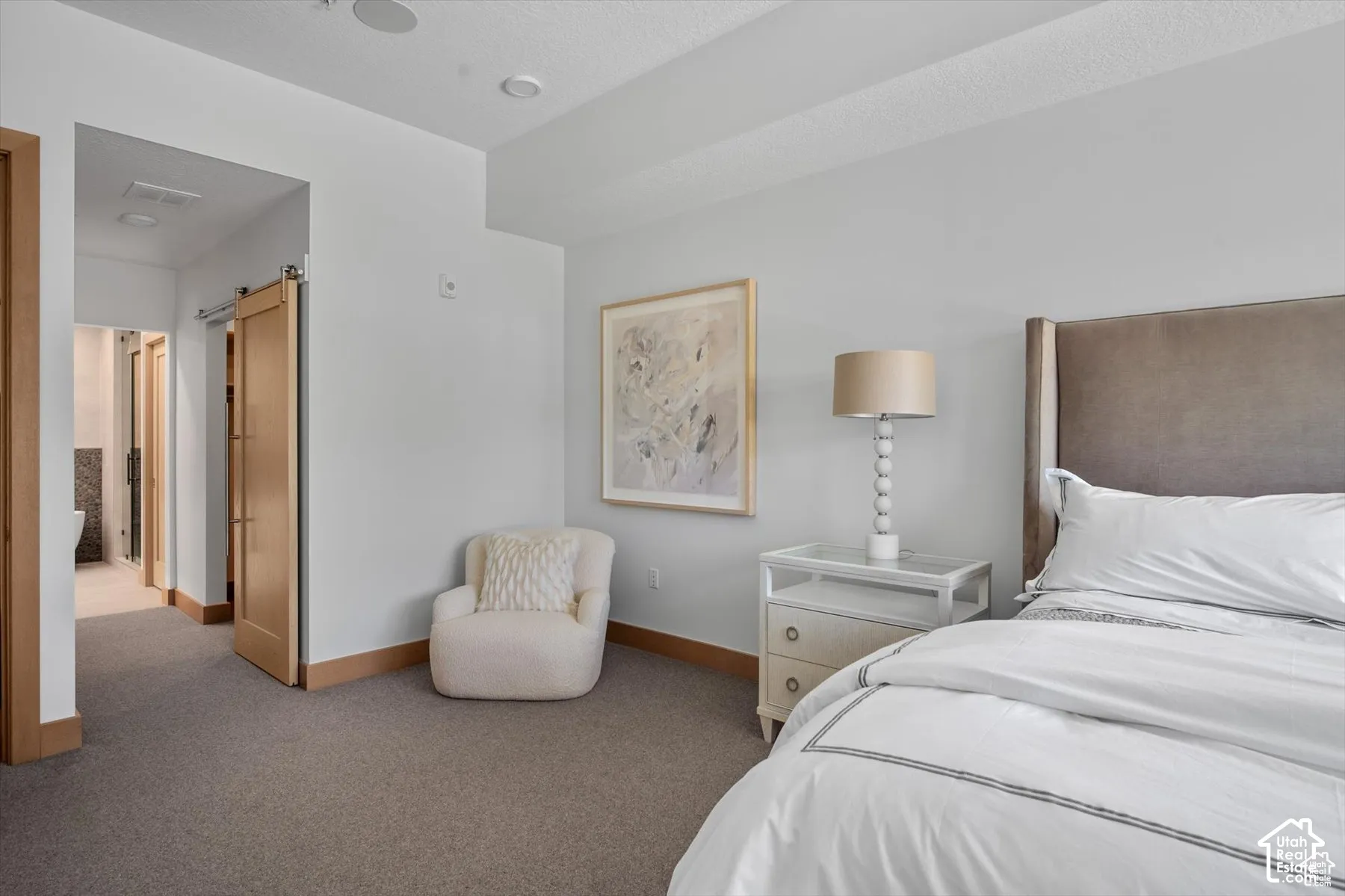 Carpeted room featuring a barn door entry to an adjacent space, wood-finish baseboards, and recessed ceiling lighting