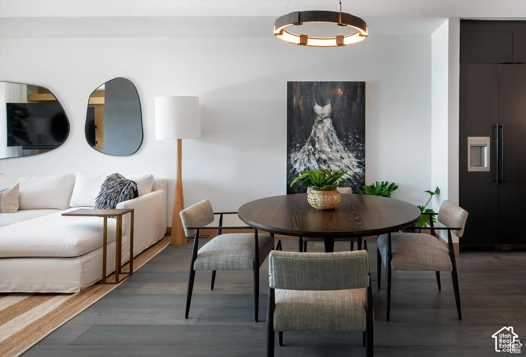 Open-concept living area with dark wood-finish flooring, a circular dining table, and a contemporary chandelier