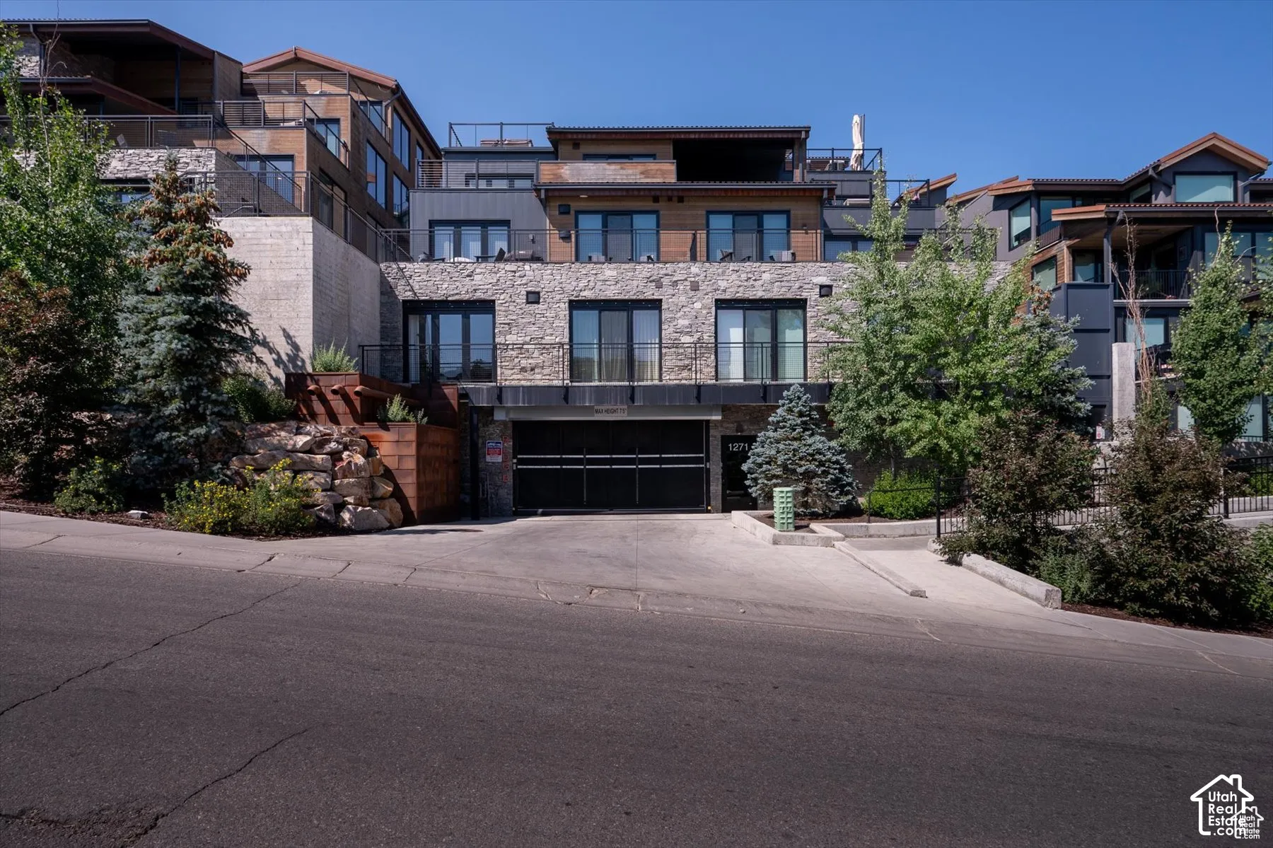 Multi-level facade featuring stone veneer, dark siding, and wood-finish accents