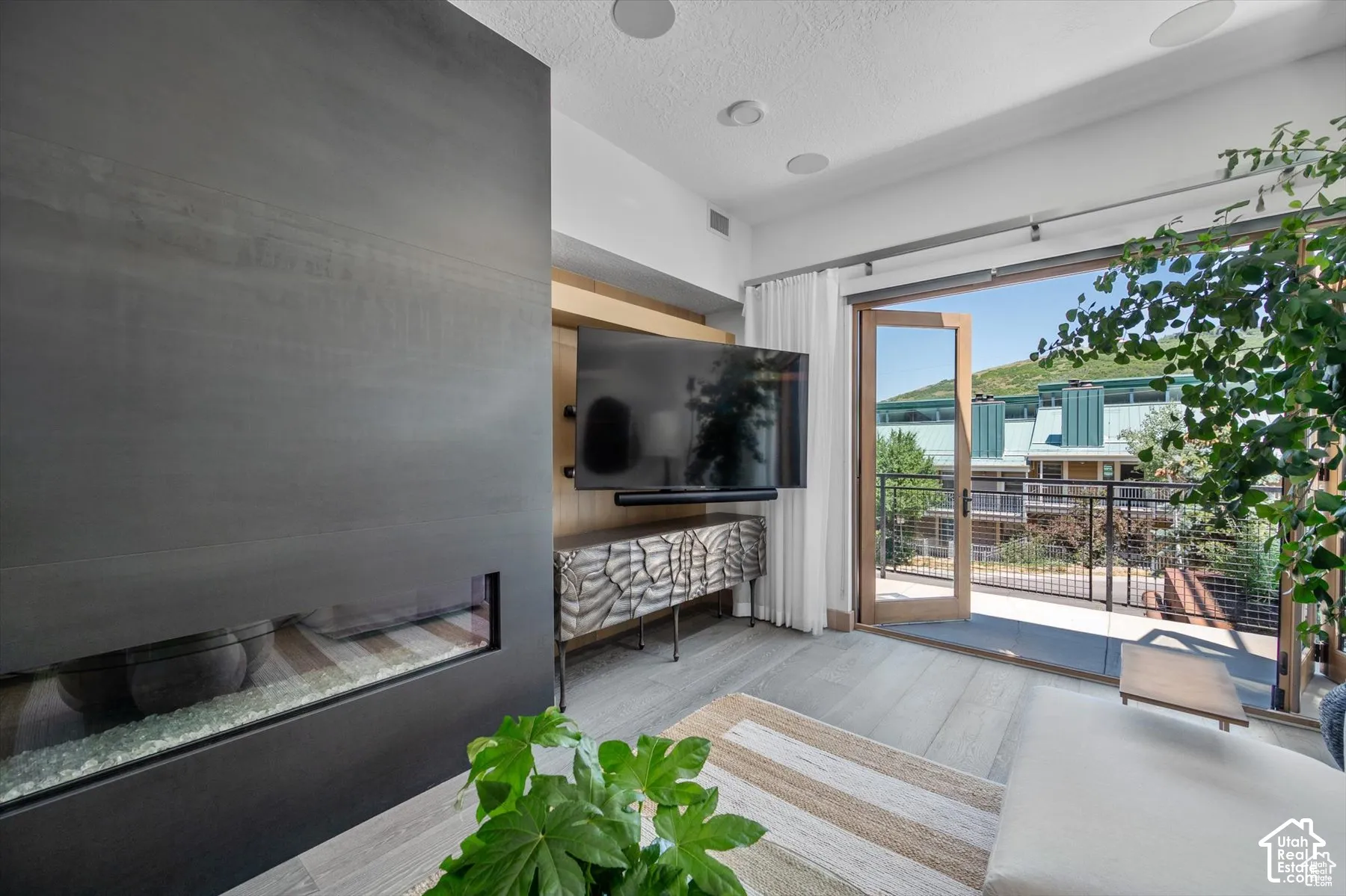 Integrated linear fireplace with glass media, wood-finish flooring, and built-in media console