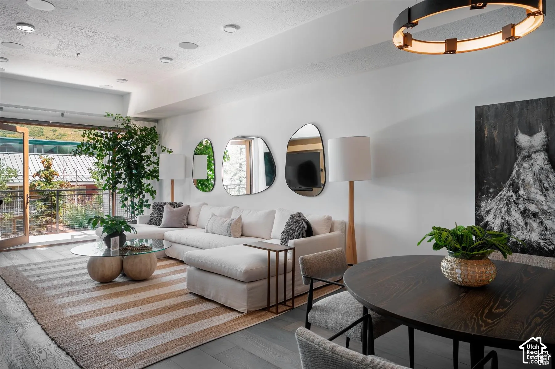 Open-concept living space featuring wood-finish flooring, recessed ceiling lighting, and a prominent balcony with double glass doors