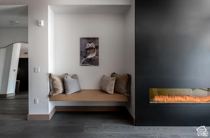 Integrated linear fireplace with a matte black surround, built-in window bench seating, and wood-finish flooring