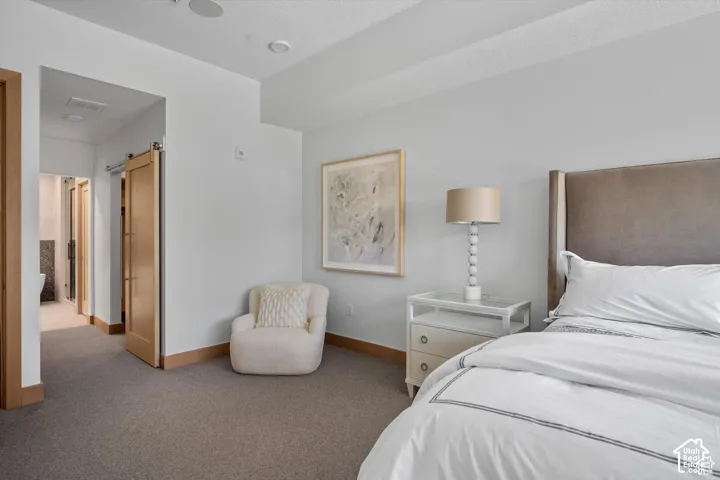 Carpeted room featuring a barn door entry to an adjacent space, wood-finish baseboards, and recessed ceiling lighting