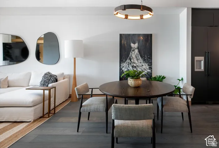 Open-concept living area with dark wood-finish flooring, a circular dining table, and a contemporary chandelier