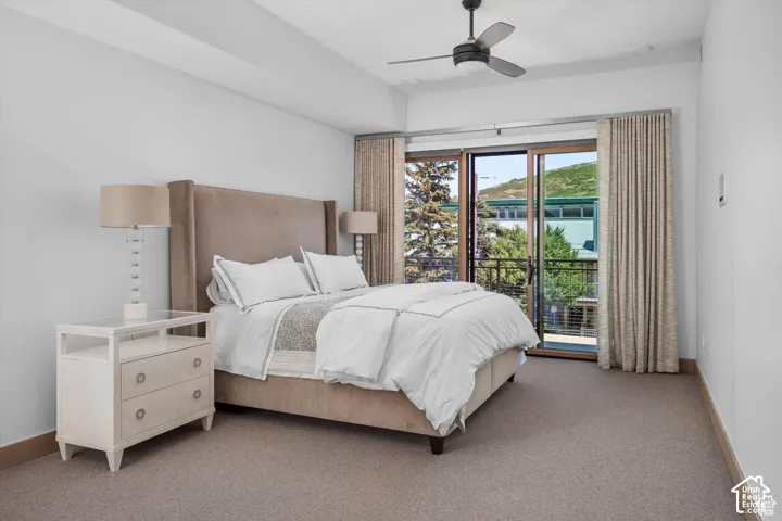 Spacious room with a ceiling fan, sliding glass door leading to a balcony, light-toned carpeting, and a neutral wall palette