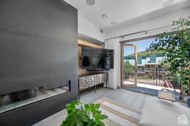 Integrated linear fireplace with glass media, wood-finish flooring, and built-in media console