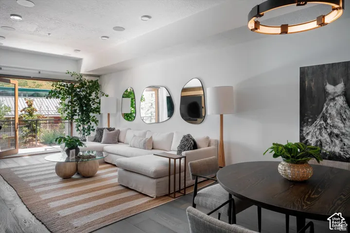 Open-concept living space featuring wood-finish flooring, recessed ceiling lighting, and a prominent balcony with double glass doors