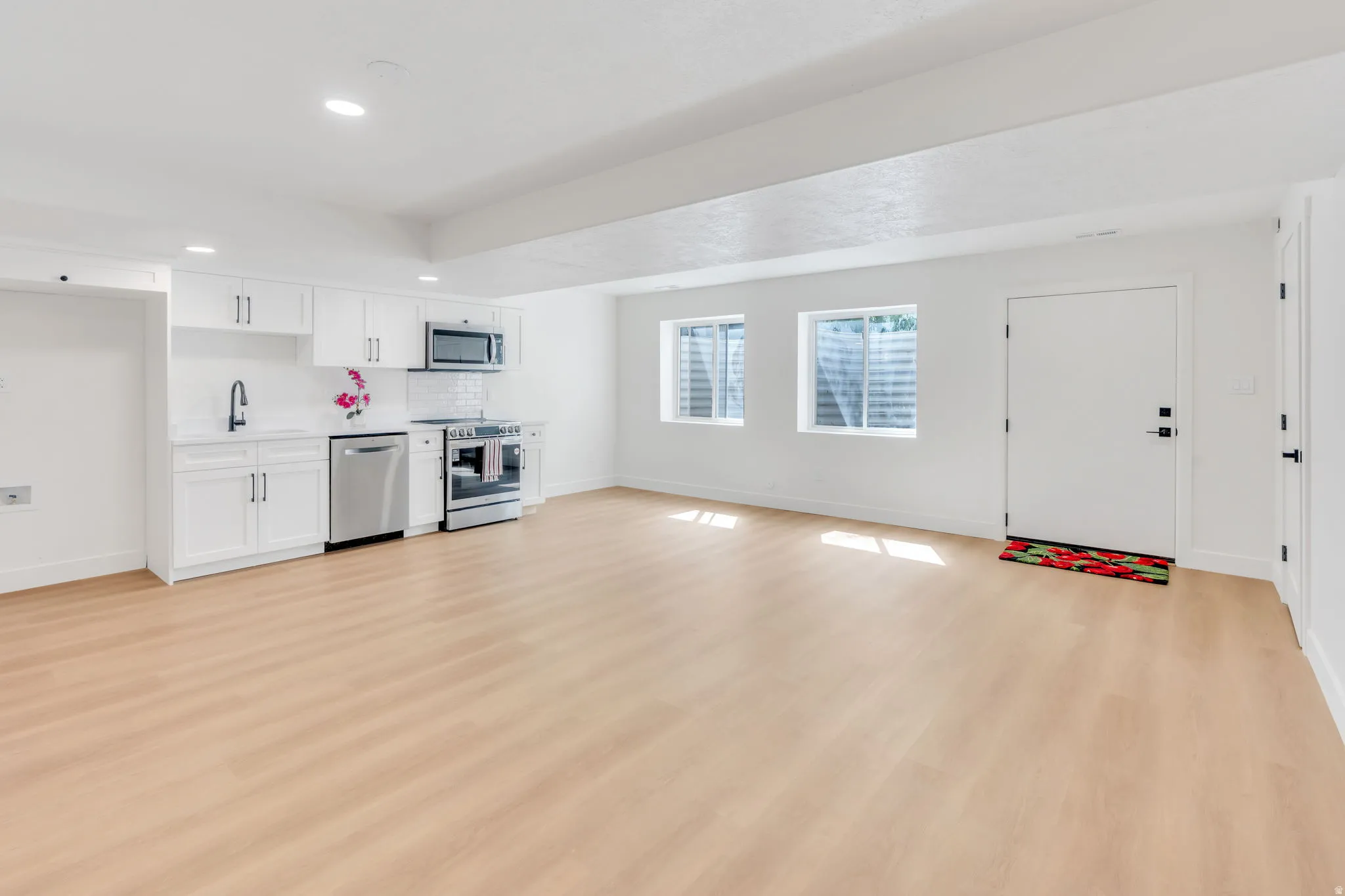 Open-concept living space with light wood-finish flooring, white walls, and recessed lighting