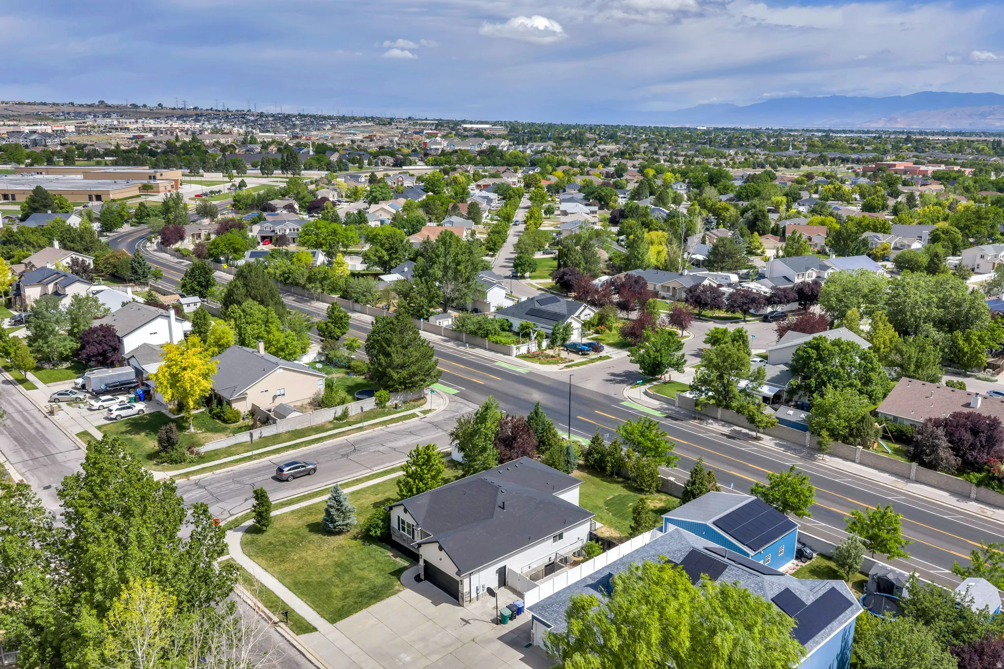 Residential neighborhood featuring mature trees, paved streets, and a variety of architectural styles under a partly cloudy sky