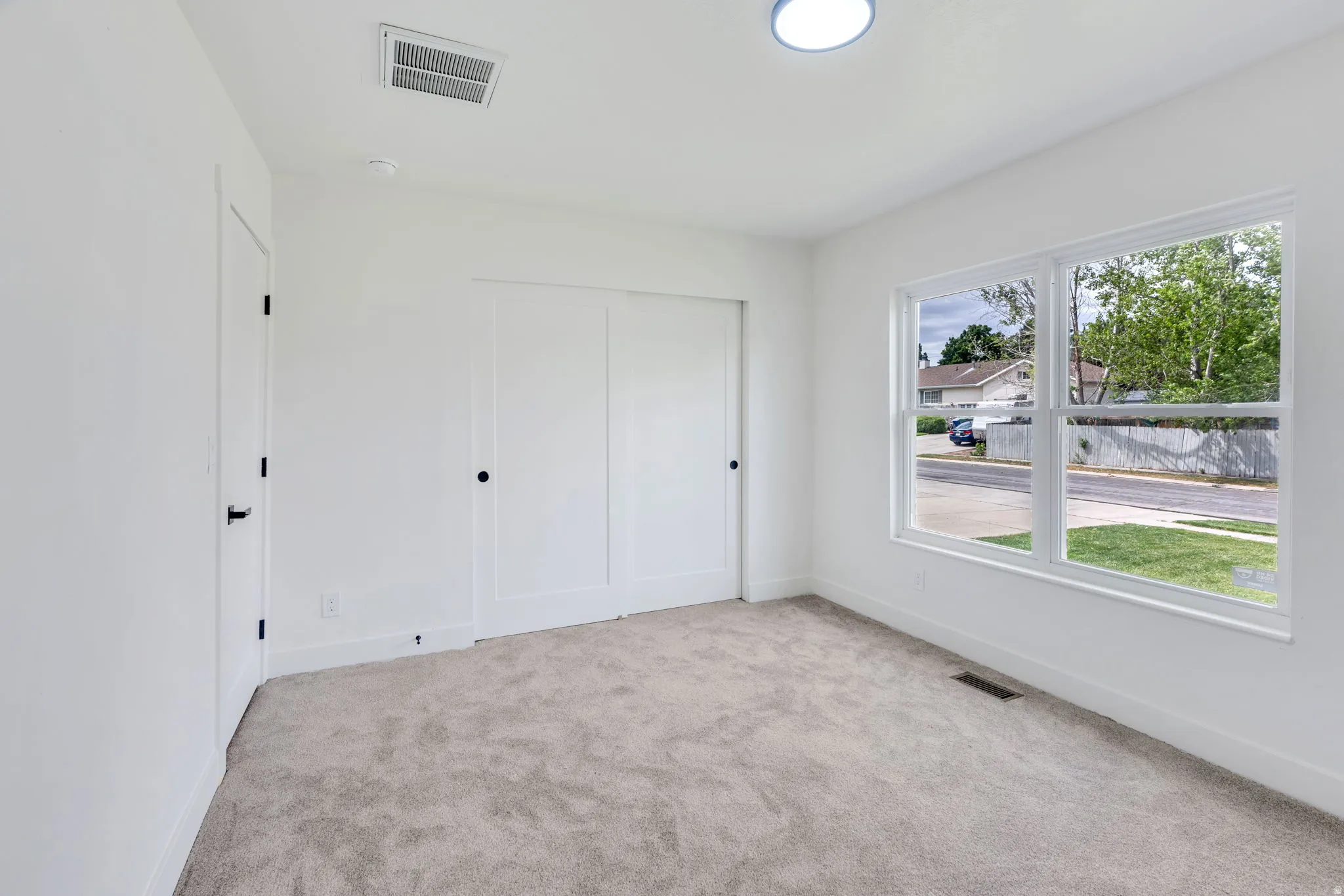Neutral-toned carpeting complements the white walls and trim throughout this room