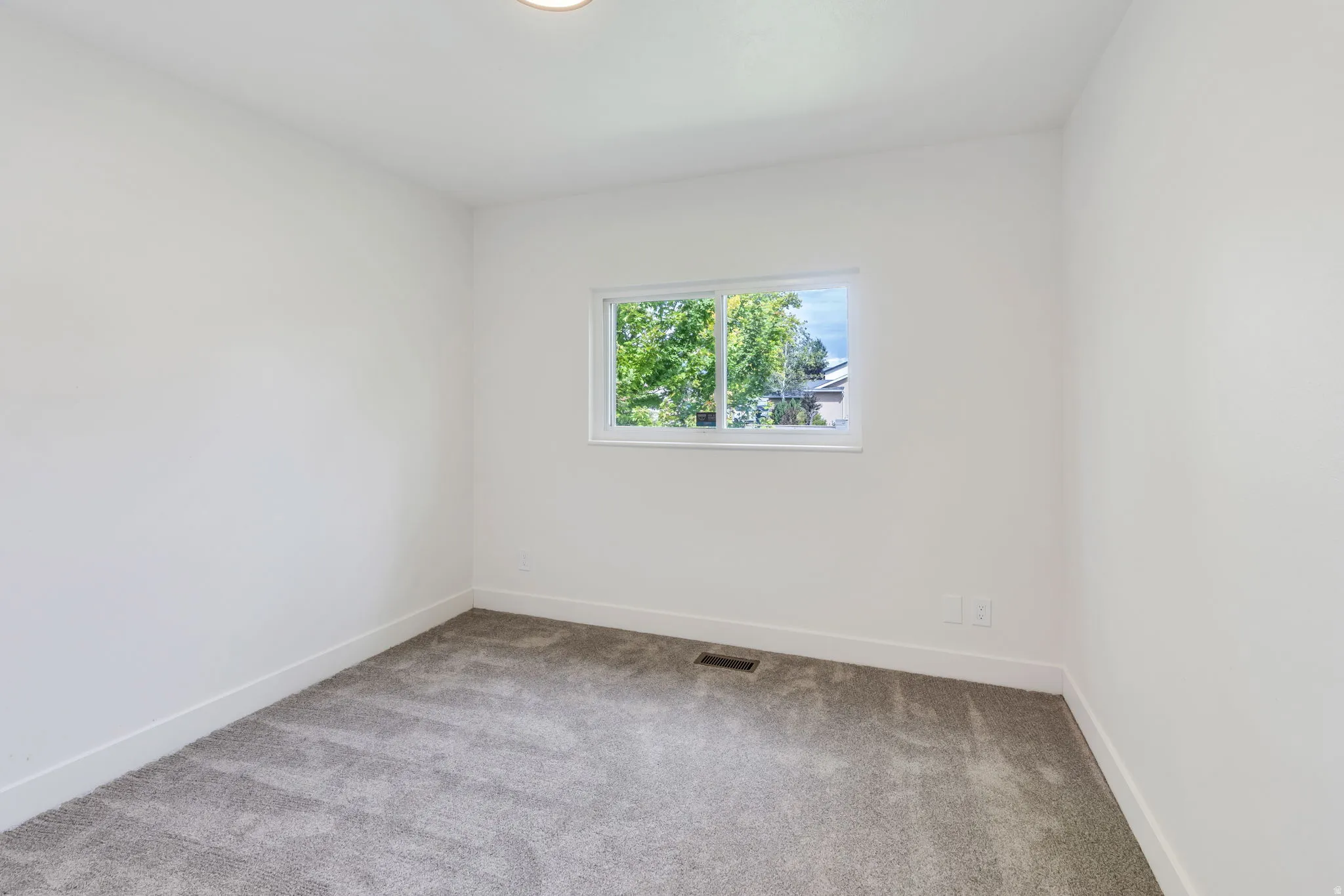 Room featuring a single window, white walls, and gray carpet flooring