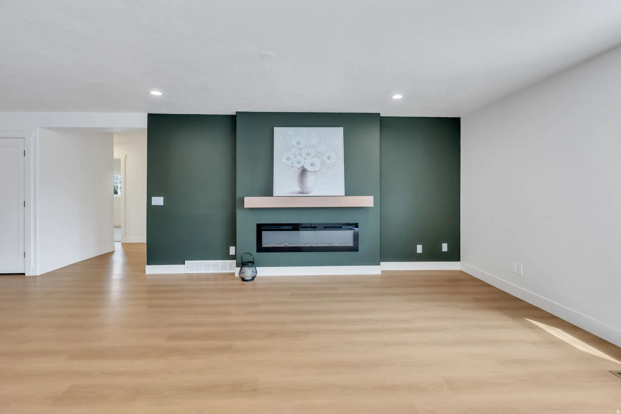 Open-concept living space featuring wood-finish flooring, recessed lighting, and a modern fireplace with a light-colored wood mantel