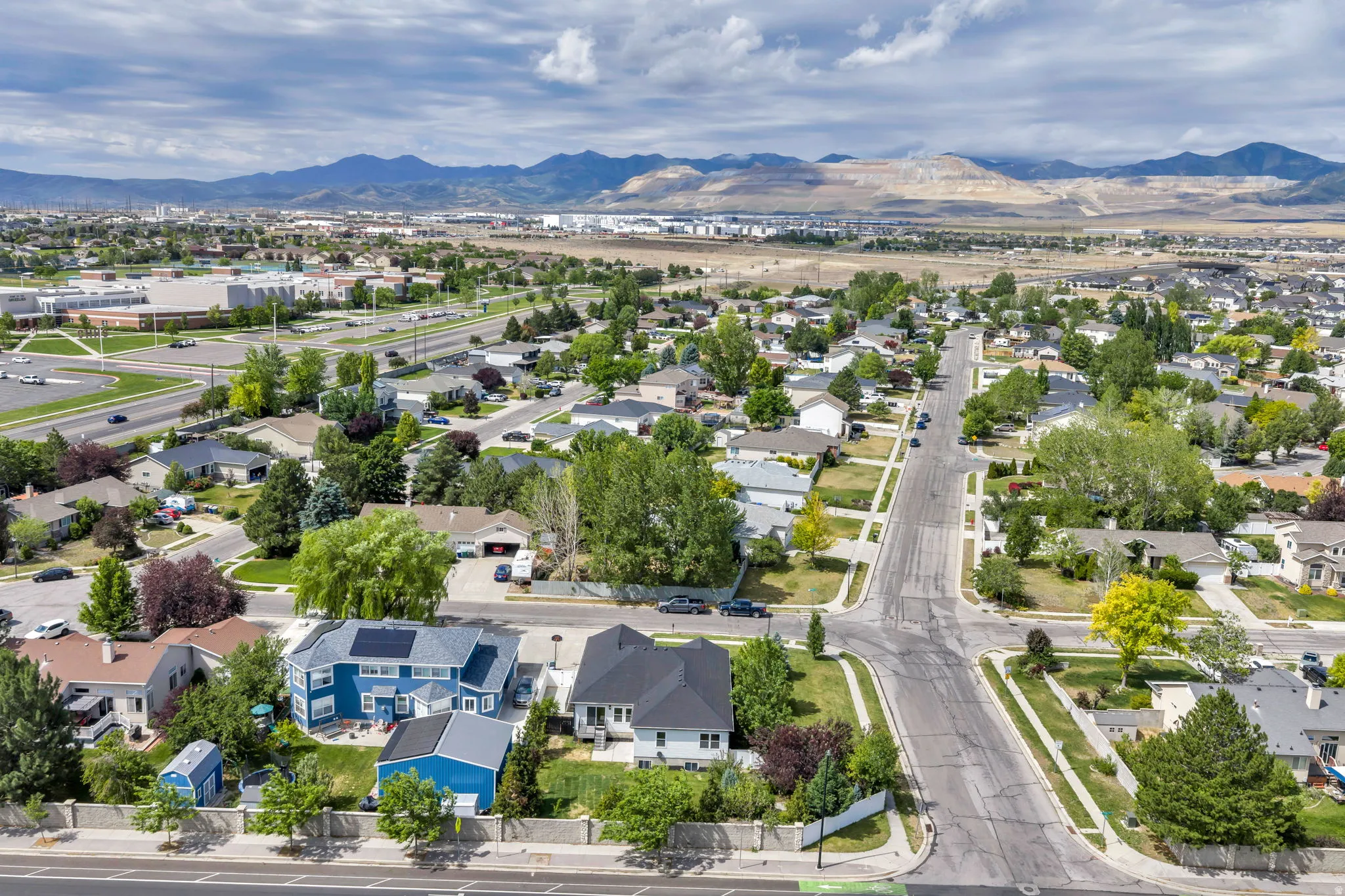 Aerial neighborhood perspective featuring residential properties, mature trees, and street infrastructure