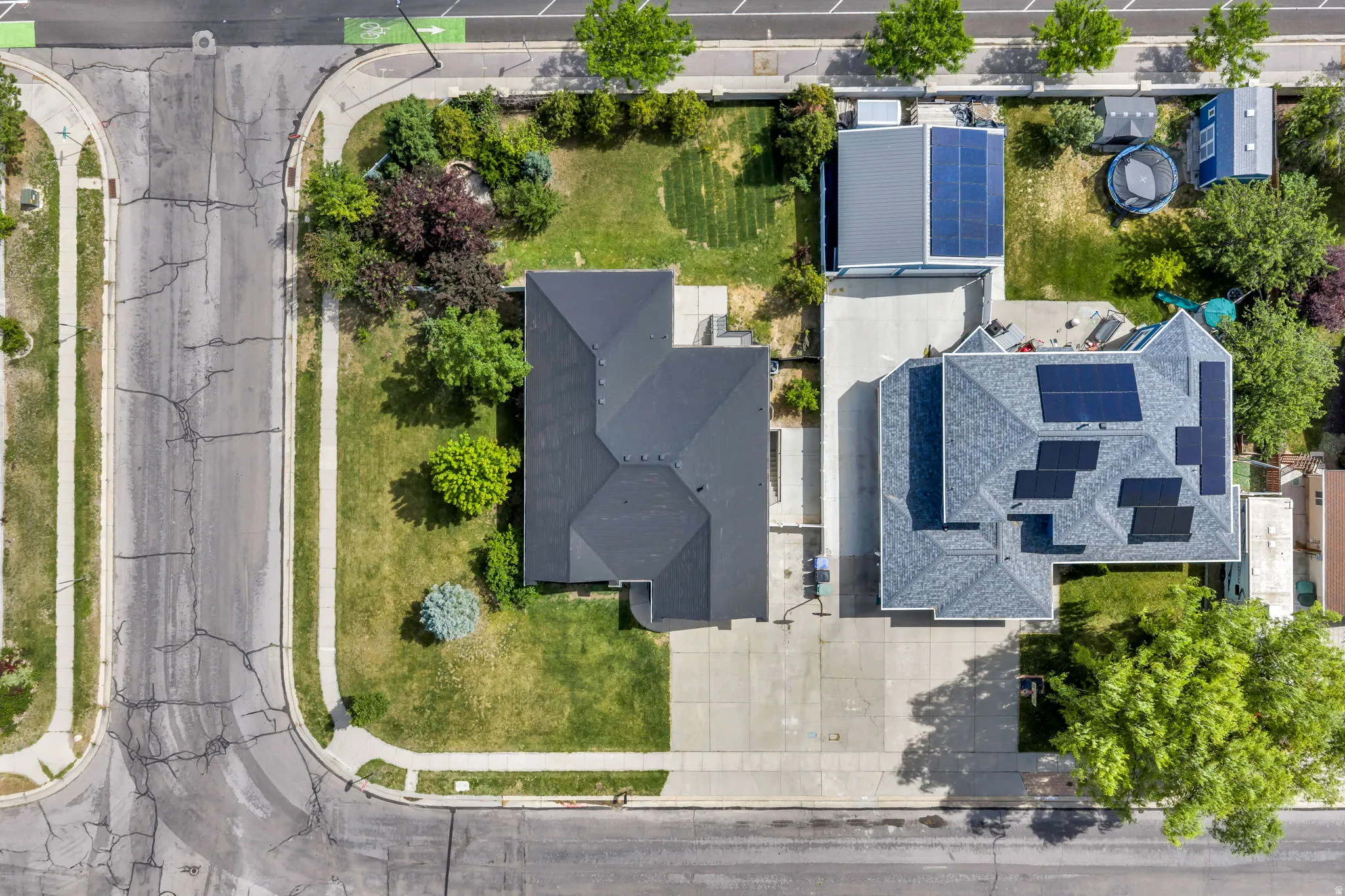 Two residences with dark shingle roofs and multiple solar panel installations