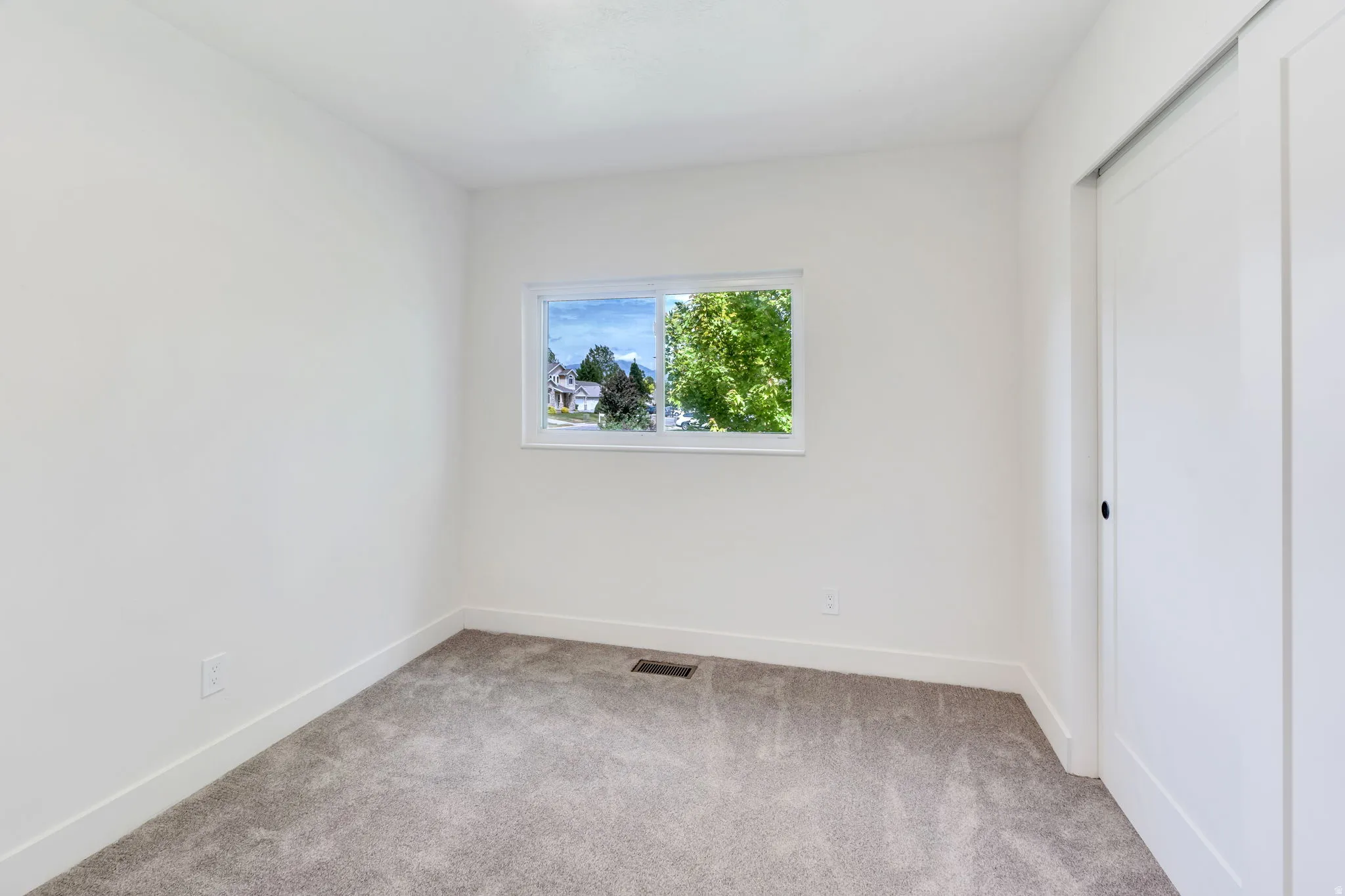 Bright room featuring neutral gray carpeting and white baseboards