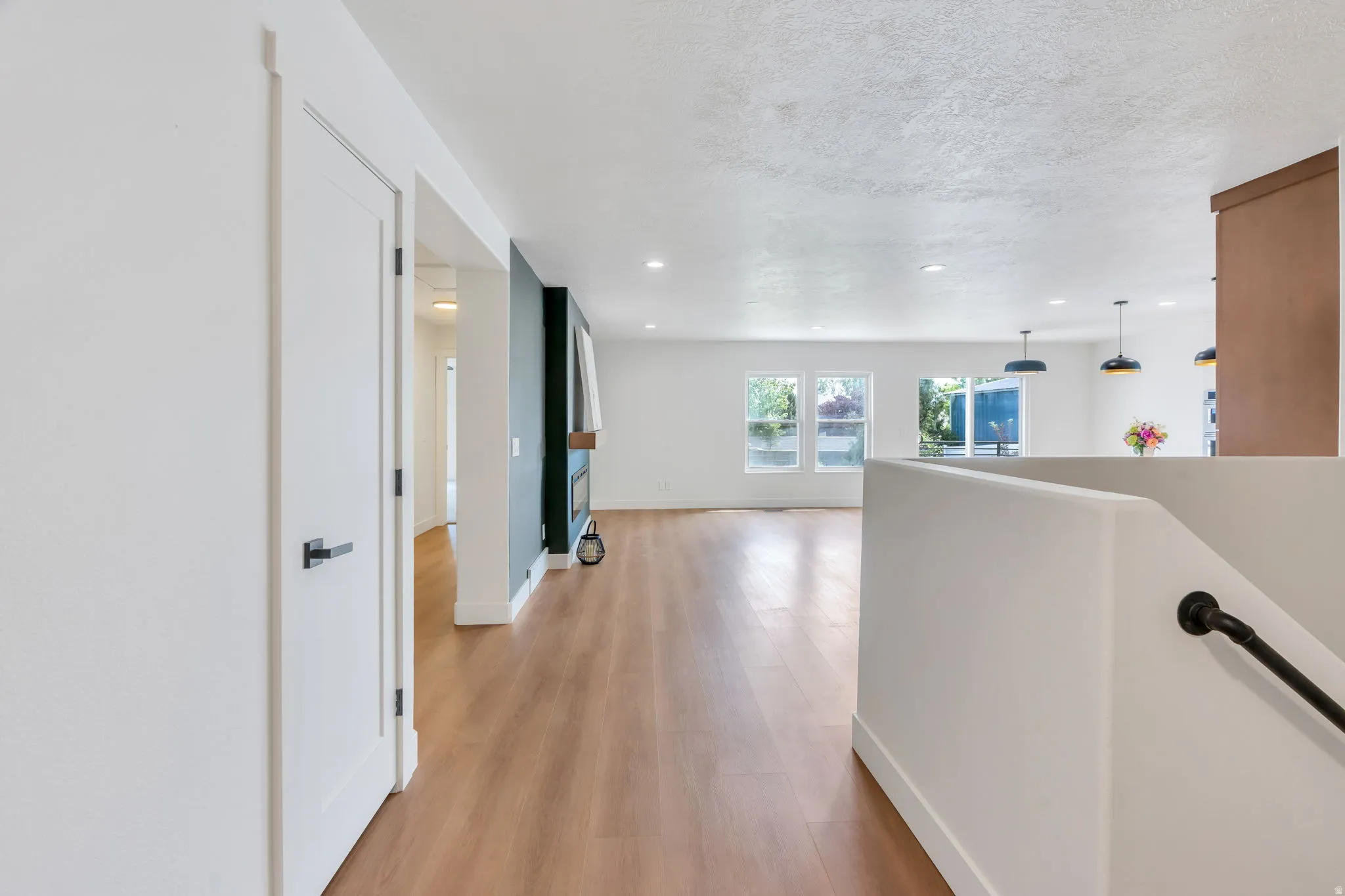 Open-concept living area with wood-finish flooring, recessed lighting, and a modern fireplace feature wall