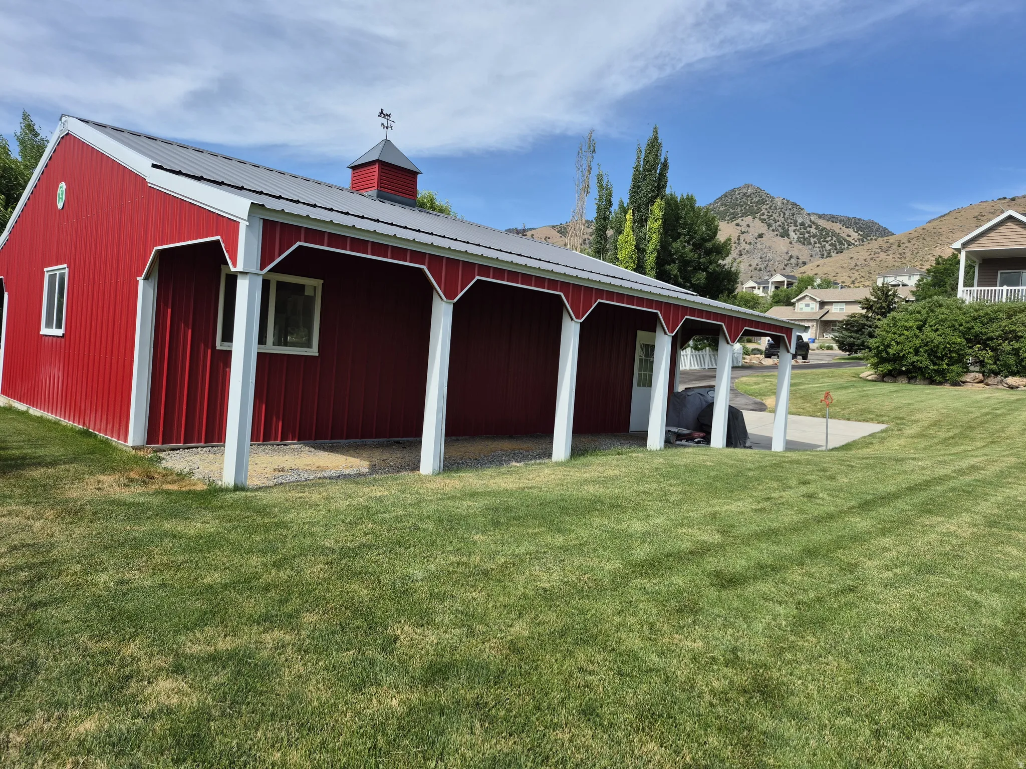 Red barn-style structure featuring a covered patio, metal roof, and cupola with a weather vane-Lots of options