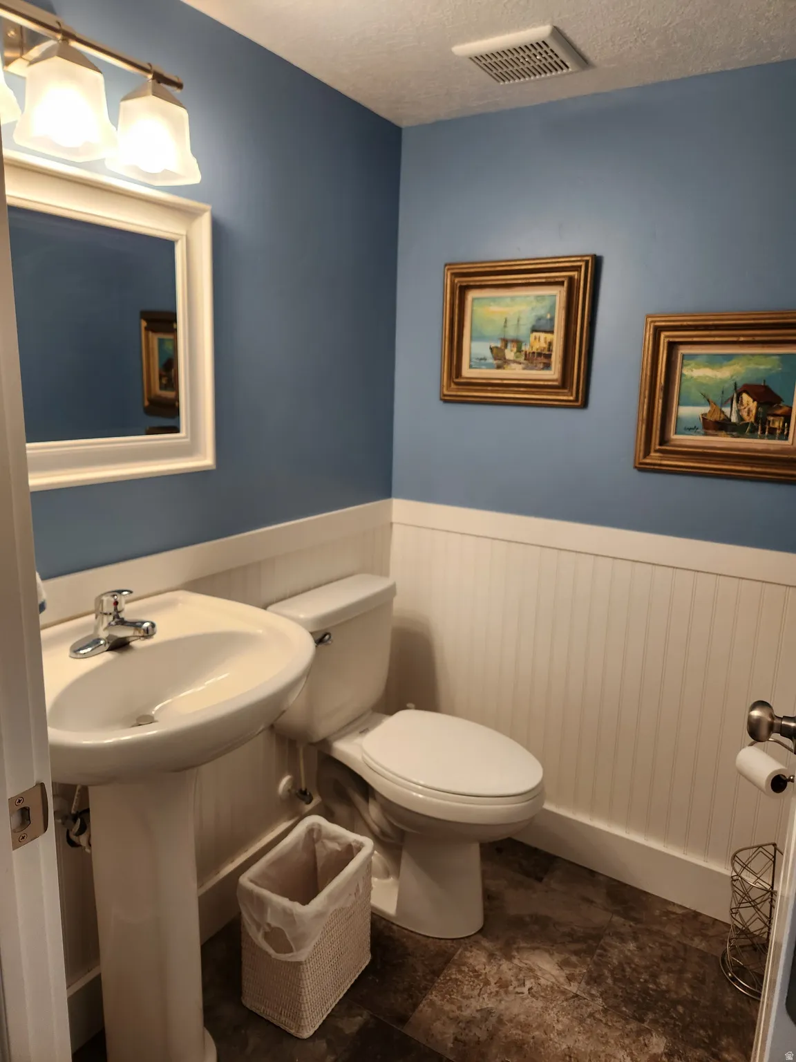 Pedestal sink with chrome faucet, white beadboard wainscoting, and blue-painted walls