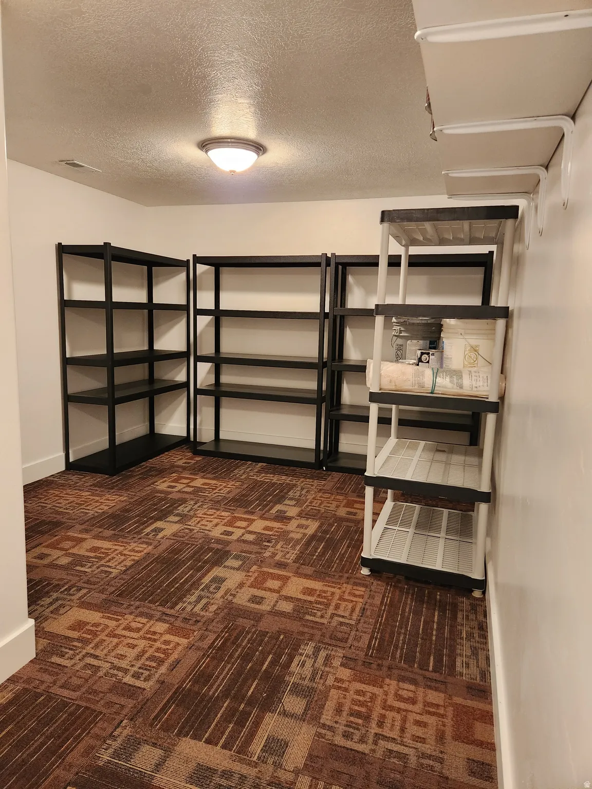 Room featuring white walls and a patterned carpet